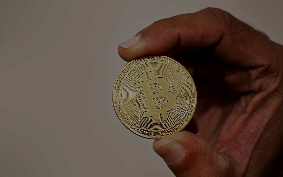 手持一枚金色的比特幣實體紀念幣